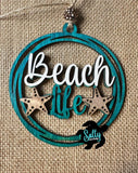 A wooden car charm with a 'BEACH LIFE' inscription, decorated with wooden stars, intended for hanging on a vehicle's rear view mirror.