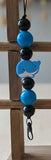 Beaded keychain with blue and black beads and a whale charm on a wooden cross.