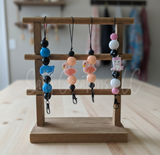 Wooden stand with colorful beaded keychains on a wooden surface