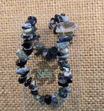 A bracelet made with black marble stones, displayed on a textured background with the brand name 'Salty Creations' visible.