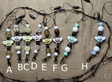 Set of bee-themed freshie hangers with beads on a textured surface