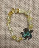 A bracelet made with yellow crystals on a textured background, displayed on a woven fabric surface.