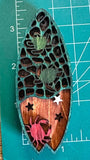 A wooden magnet shaped like a surfboard with a crab and turtle design with measuring mat in background measuring 3.5 inches