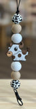 Beaded Freshie Hanger with cow design on a wooden surface