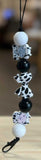 Freshie Hanger with black, white, and cow print beads on a wooden surface