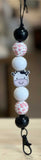 Freshie Hanger with cow face design on a string against a blurred background