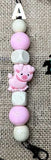 Strand of beads with a pink pig charm on a textured fabric background