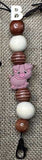 Lanyard with pig charm and beads on a textured fabric background