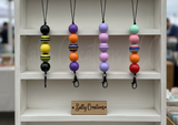 Colorful beaded keychains on a shelf with 'Sally Creations' sign.