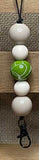 Lanyard with white and green beads on a wooden surface