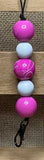 Keychain with pink and white beads on a wooden surface