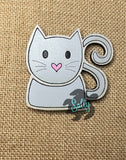 A magnet shaped like a stylized cat with a gray color and a heart on its chest, made from wood.