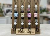 Collection of colorful bear-shaped keychains on a wooden stand with 'Freshie Hangers' branding.