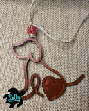 Handmade wooden dog silhouette car charm with a red heart inlay, and red acyrlic bead on burlap background