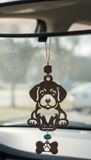 Handmade wooden puppy car charm with a bone and paw print cutout, featuring a turquoise bead and tan twine, hanging from a car rearview mirror.