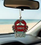 Car wooden charm shaped like a crab with text hanging from a car's rearview mirror.
