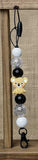 Decorative keychain with beads and a small bear figure on a wooden surface.