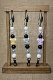 Three beaded keychains with koala bear charms on a wooden stand against a textured brown background.
