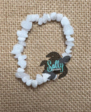 A bracelet made with white labradorite stones, featuring a mix of clear and translucent patterns, displayed on a textured background.