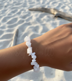 White stone bracelet on a wrist with a beach background