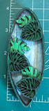 A decorative surfboard-shaped object with leaf patterns on a measuring mat background.