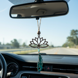 Car interior with a decorative hanging ornament featuring a lotus flower design.