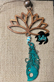 A wooden car charm with a lotus flower design, featuring hanging tyrquoise wooden feather and strings and a small beaded ornament.