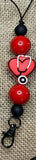 Hanger with red and black beads and a heart-shaped charm on a textured background