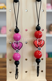 Two Freshie Hangers with heart designs on a wooden pegboard.