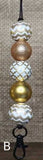 Decorative keychain with gold, silver, and white beads on a textured background