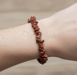 Brown stone bracelet on a wrist with a neutral background