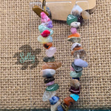 A multicolored beaded bracelet with a variety of shapes and colors, displayed on a textured background.