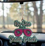 Car charm with sunglasses design and text 'No One likes a Shady Beach' hanging from a car's rearview mirror.