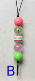 Colorful beaded phone charm on a gray background with a blue 'B' label.