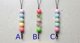 Three colorful beaded freshie hangers labeled A, B, and C on a gray surface.