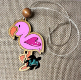 Pink wooden flamingo ornament with a brown wooden bead and twine string. The flamingo has a pink heart-shaped wing.