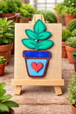 Colorful wooden plant decoration with a heart on a small easel surrounded by potted plants.