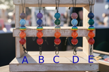 Colorful beaded Frreshie Hangers on a wooden stand with letters A to E.