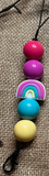 Colorful beaded freshie hanger with a rainbow charm on a textured surface