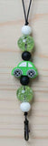 Necklace with green car charm and beads on a wooden surface