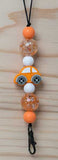 Lanyard charm with orange car and beads on a wooden surface