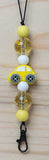 Yellow car-shaped charm with beads on a wooden surface