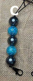 Black and blue beaded Freshie Hanger with a letter 'C' on a textured beige background