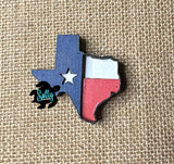 A magnet shaped like the Texas flag, with blue, white, and red colors, placed on a burlap background.