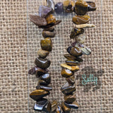 A bracelet made with multiple brown stone beads, displayed on a textured background.