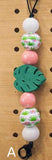 Decorative keychain with colorful beads and leaf-shaped charm on a wooden pegboard.