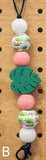 Beaded keychain with floral-patterned beads and green leaf-shaped charm on a wooden background