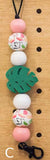 Decorative keychain with colorful beads and leaf charm on a wooden surface