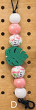 Decorative keychain with colorful beads and a leaf charm on a wooden pegboard background.