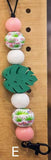 Decorative keychain with floral beads and green leaf on a wooden surface
